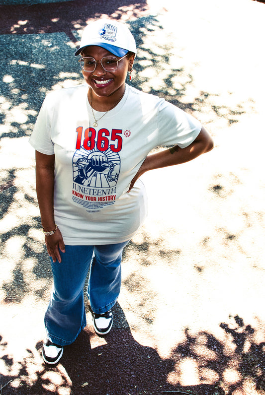 Model wearing Juneteenth 'Know Your History' tee in bone, standing face forward to display front graphic with raised fist and 1865 design