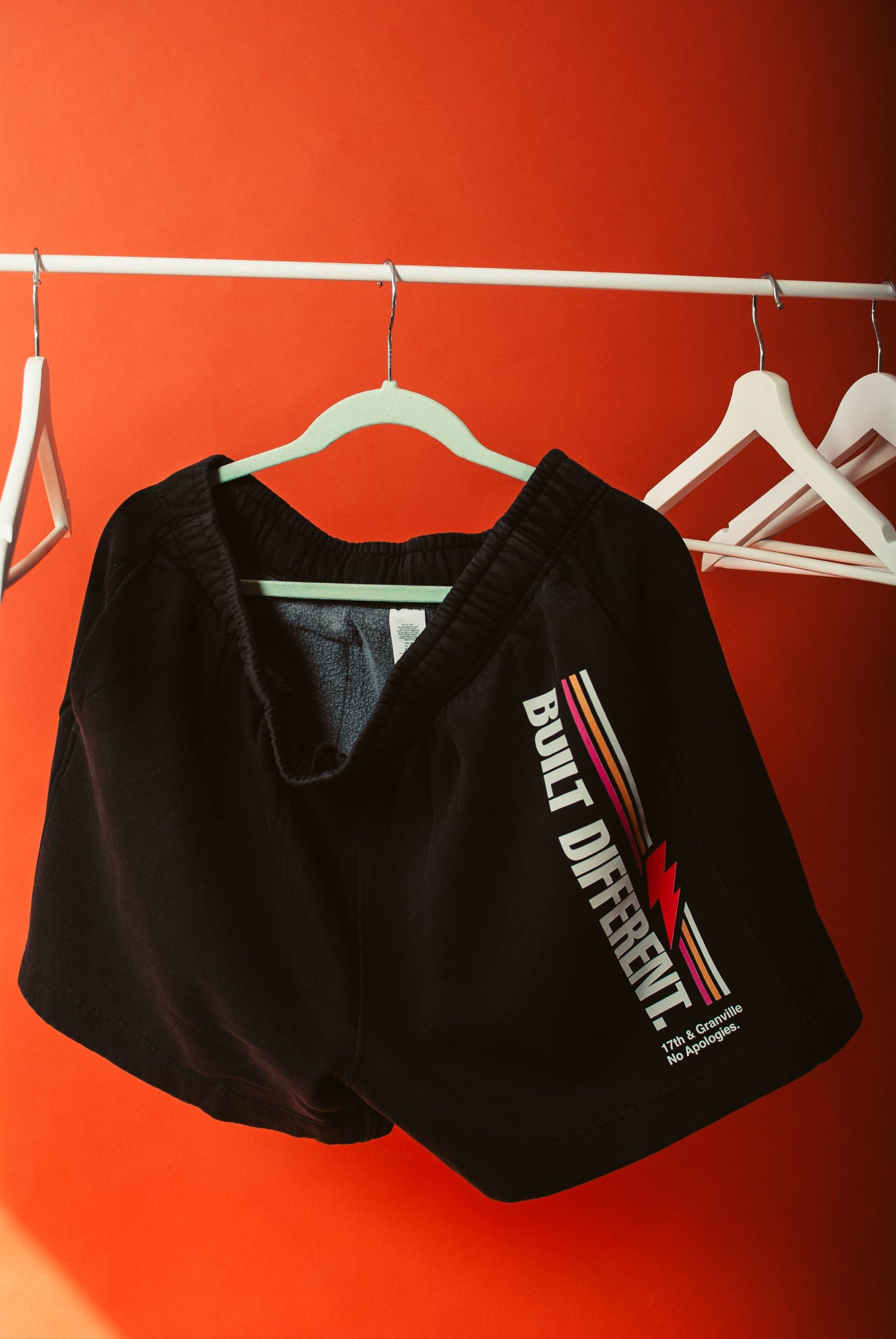 No apologies shorts on a hanger against an orange wall