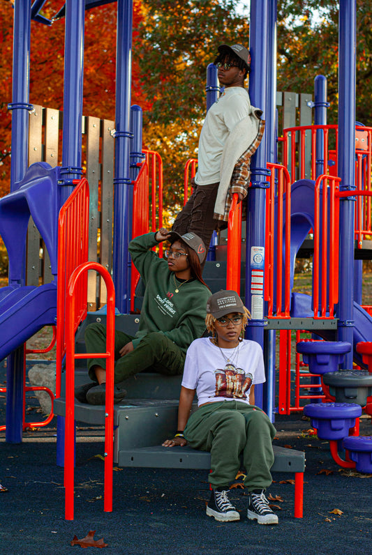 Three models sitting in a park wearing items from the We US collection.