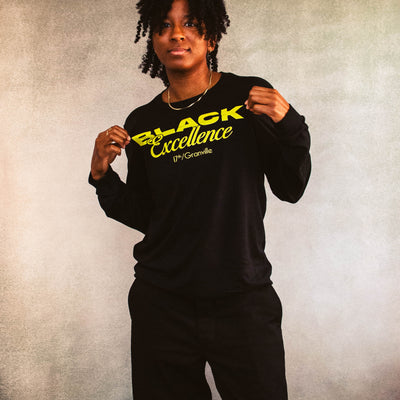 Person wearing a black sweatshirt with 'Black Excellence' text on a textured background