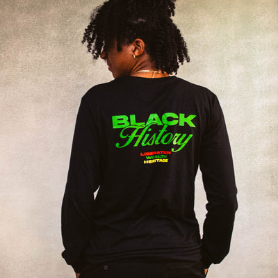 Person wearing a black long-sleeve shirt with 'Black History' text on the back against a textured beige background