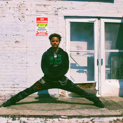 BIPOC model wearing black organic Eintou Collection hoodie with embroidered design, showcasing empowered expression. Part of 17th & Granville's fashion activism collaboration supporting BIPOC and LGBTQ+ communities.