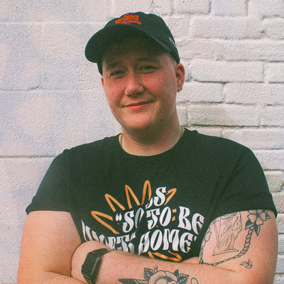 Black organic cotton hat and t-shirt from the Eintou Collection by 17th & Granville, featuring embroidered design with poetry snippets, part of a fashion activism collaboration supporting BIPOC and LGBTQ+ communities.