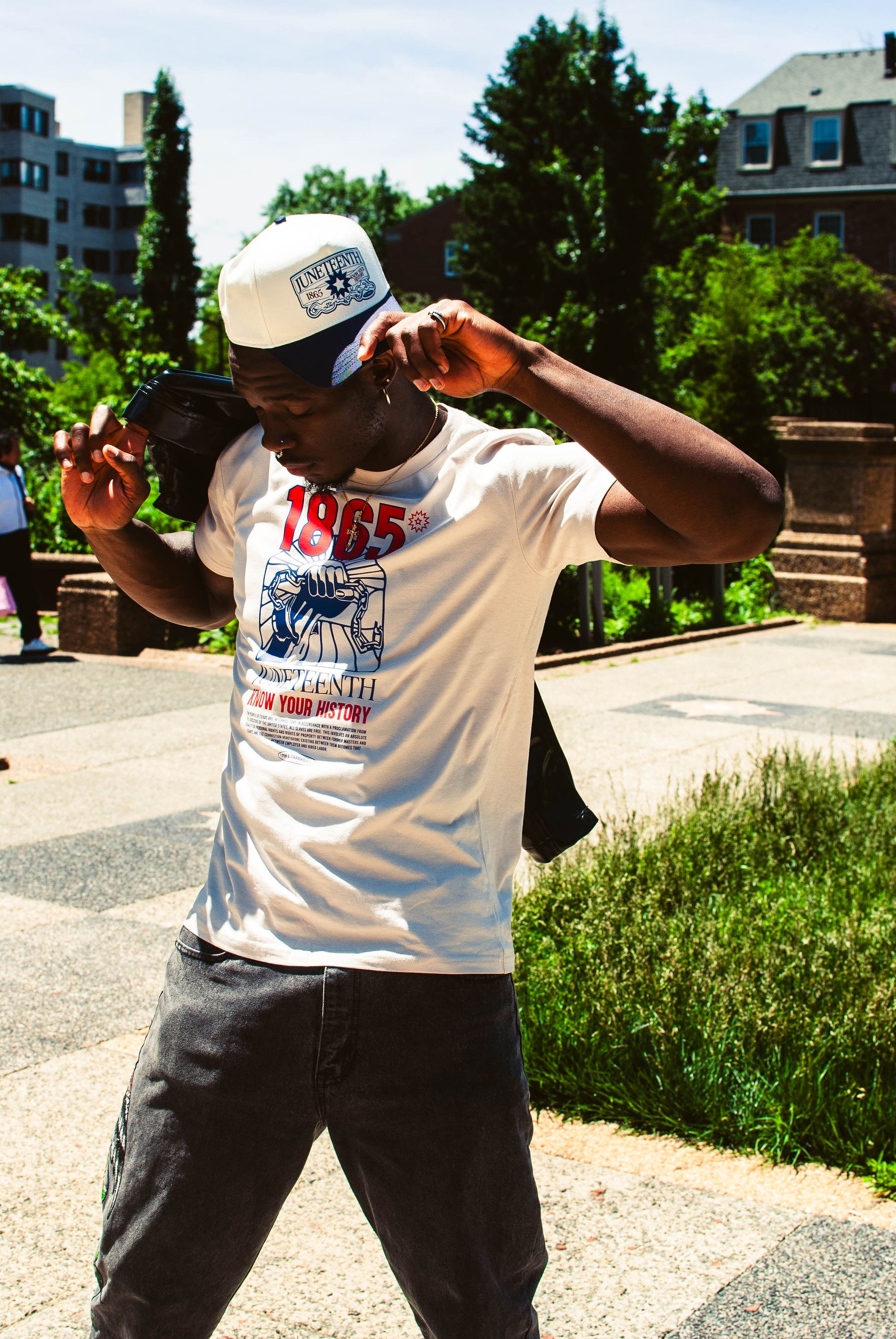 Side profile of model wearing bone-colored Juneteenth shirt, showcasing relaxed fit and subtle structure of tee