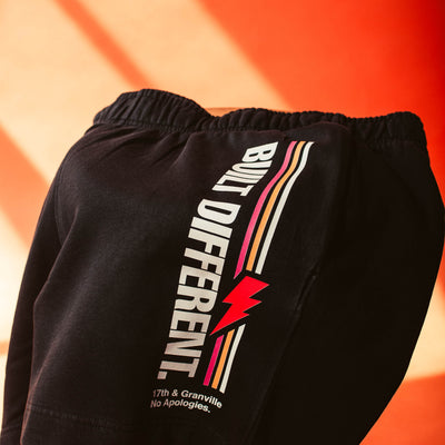 No apologies shorts with 'Built Different' text and logo on an orange background