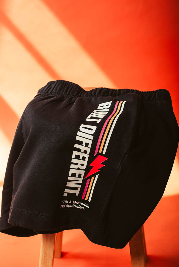 No apologies shorts with 'Built Different' text and logo on an orange background