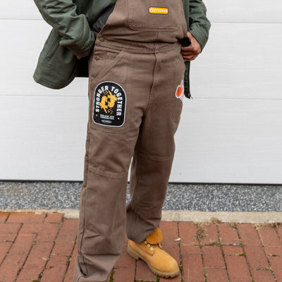 Close up of brown We Us overalls.