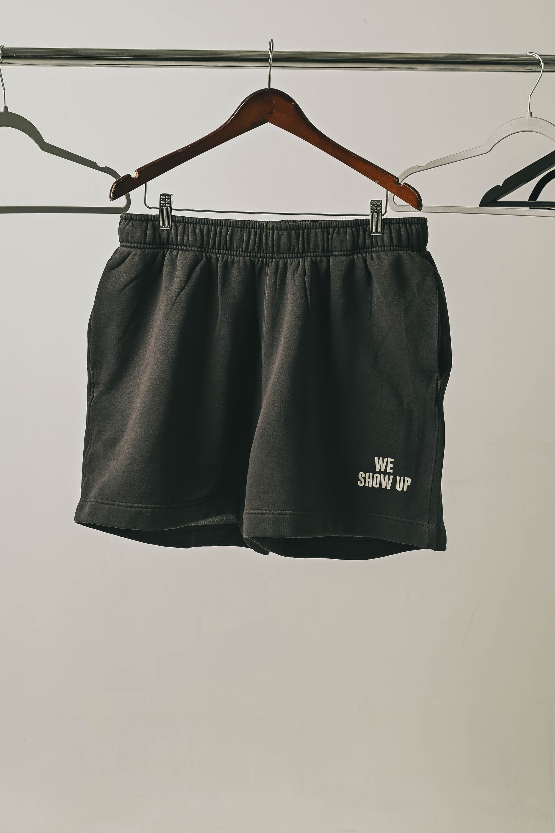 We Show Up Grey shorts on a hanger